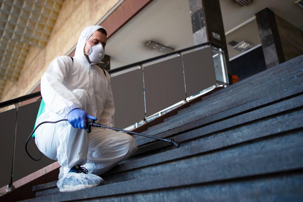 a man in protective suit disinfecting the stairs