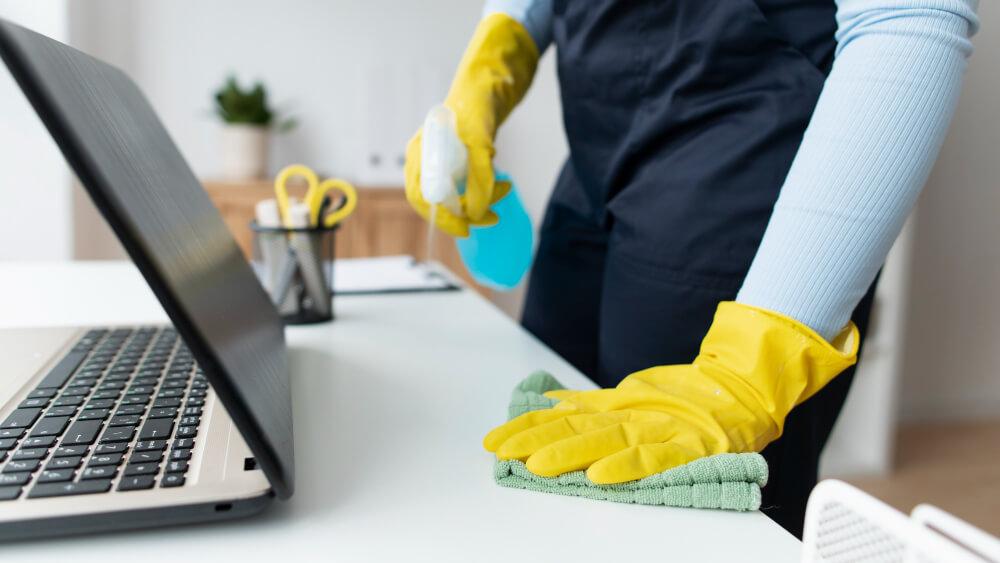 a person with gloves wiping the desk